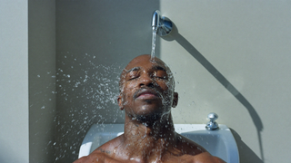 Wrestler splashing cool water on his face at a gym sink after practice