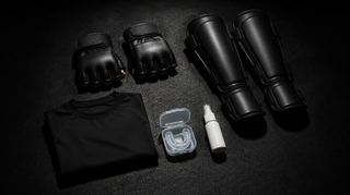MMA equipment for beginners: MMA gloves, shin guards, gum shield, rashguard and hygiene spray on a gym floor