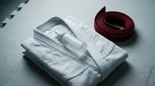 A folded white gi with a skin mist bottle, mat etiquette and cleanliness for beginners