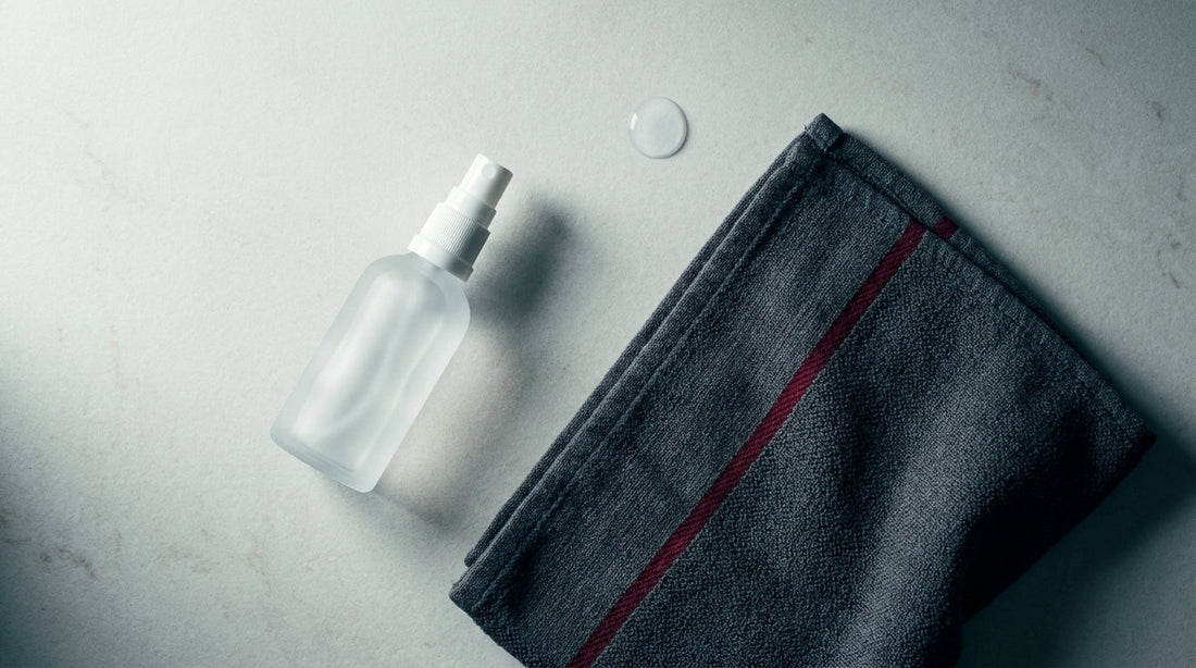 Flat-lay of a clear skin mist bottle and folded towel, a post-training skin cleansing routine