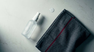 Flat-lay of a clear skin mist bottle and folded towel, a post-training skin cleansing routine