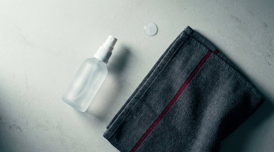 Flat-lay of a clear skin mist bottle and folded towel, a post-training skin cleansing routine