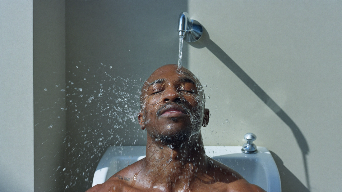 Wrestler splashing cool water on his face at a gym sink after practice