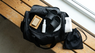 Wrestling gym bag flat lay with soap bar, skin mist, shower slides and towel