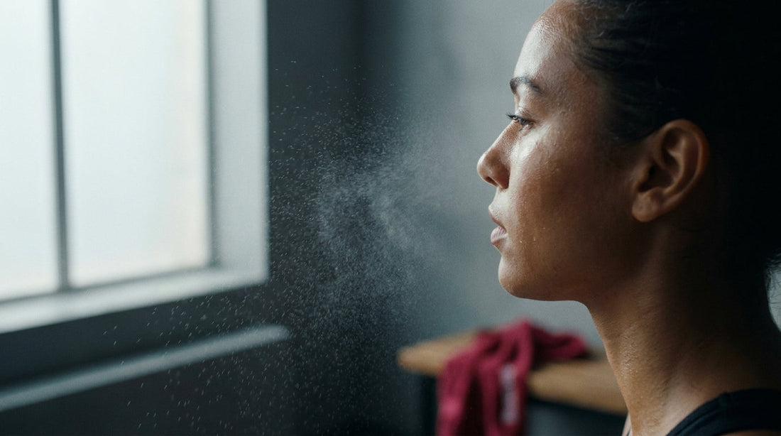 Fine facial mist droplets suspended in light in front of dewy post-workout skin