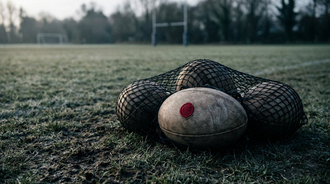 Rugby balls in a net bag at the edge of a training pitch - coach's guide to sanitizing balls and equipment