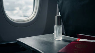 Travel-size facial mist bottle on an aircraft tray table by the window with clouds outside
