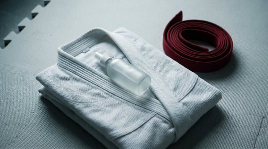 A folded white gi with a skin mist bottle, mat etiquette and cleanliness for beginners
